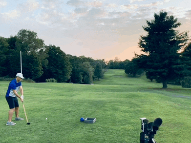 a man is swinging a golf club at a golf ball on a golf course