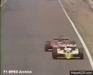 a race car is going around a curve on a track and smoke is coming out of it .