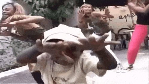 a group of women are dancing in a room with a boy making a face .