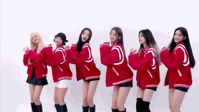 a group of young women wearing red varsity jackets are standing next to each other and dancing .