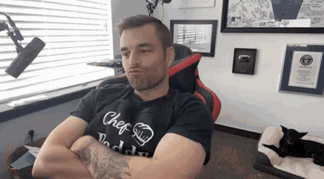 a man sitting in a chair with his arms crossed and a shirt that says chef guy