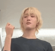 a young man with blonde hair and a black shirt is making a fist .