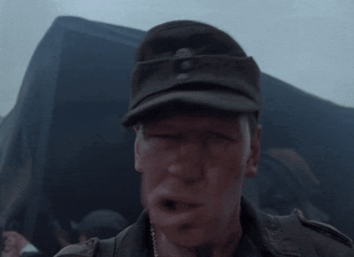 a man in a military uniform is blowing a whistle in front of a tent .