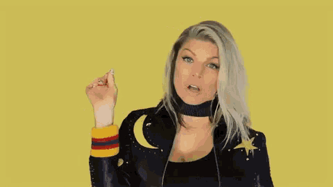 a woman in a black leather jacket with a crescent moon and star on it is pointing at something .