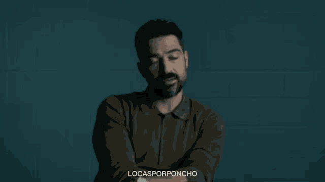 a man with a beard is standing with his arms crossed and his eyes closed .