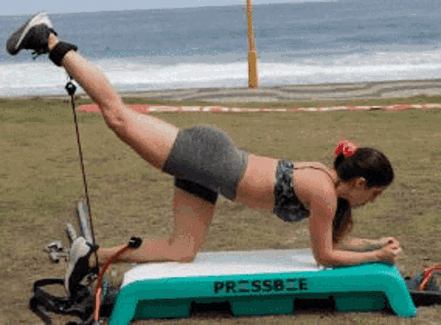 a woman is doing leg exercises on a green pressbee platform