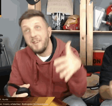 a man in a red sweatshirt is giving a thumbs up