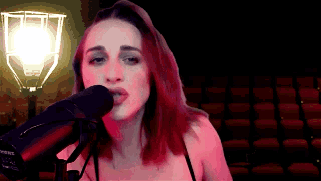a woman singing into a shure microphone in front of an auditorium