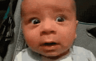 a baby is making a funny face with his mouth open .