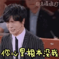 a man in a suit and tie is sitting in front of a microphone with chinese writing on it .