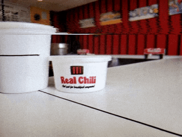 a cup of real chili sits on a white table