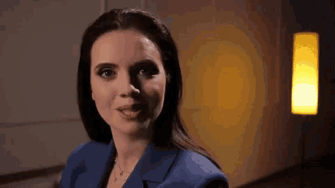a woman in a blue suit is standing in front of a lamp .
