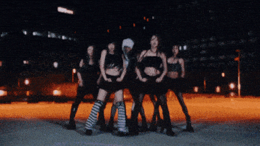 a group of women are dancing together in a dark room