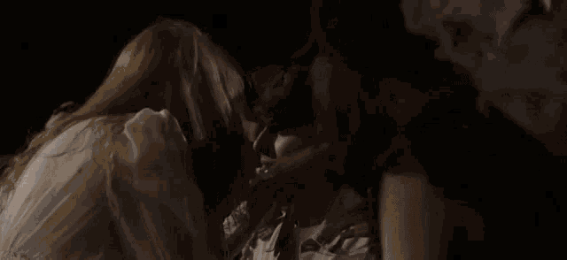a couple of women are kissing each other in a dark room .