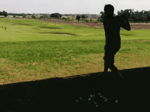a man is swinging a golf club at a golf course