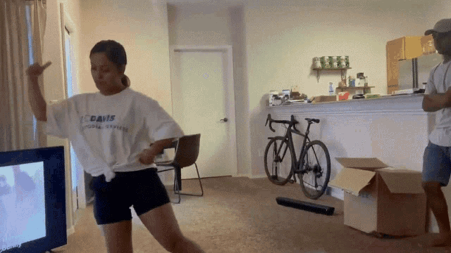 a woman wearing a white shirt that says " canis " is dancing in a living room