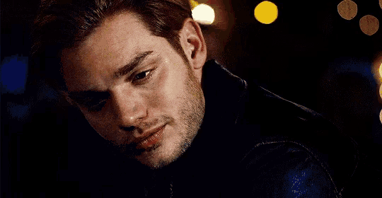 a close up of a man 's face with a beard wearing a black jacket .