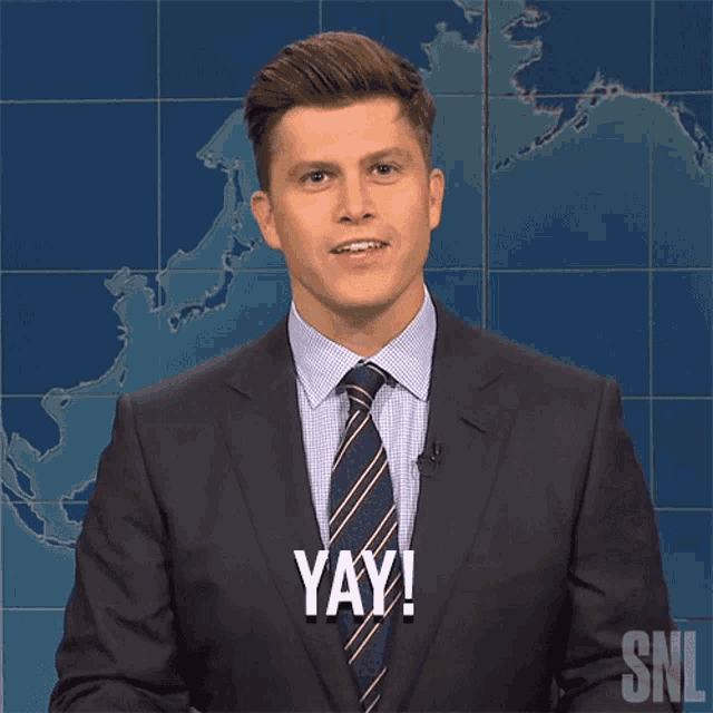 a man in a suit and tie says yay with his hands in the air