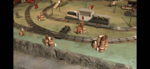 a toy train set with barrels and a building that says coca cola