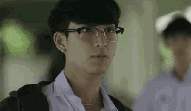 a man wearing glasses and a white shirt looks at the camera