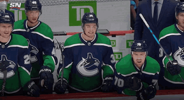 a group of hockey players wearing blue and green jerseys with the number 24 on the front