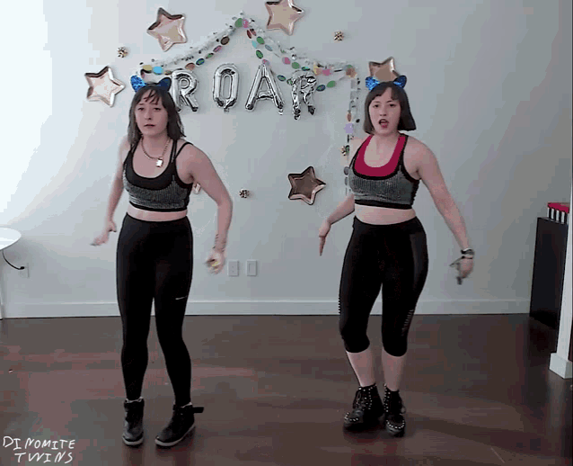 two women dancing in front of a roar balloon