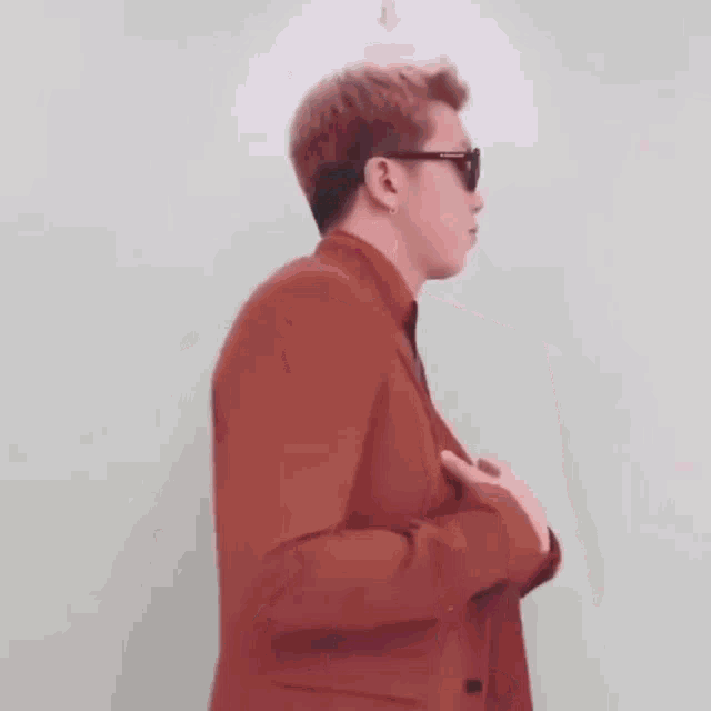 a man in a suit and tie is standing in front of a white wall .