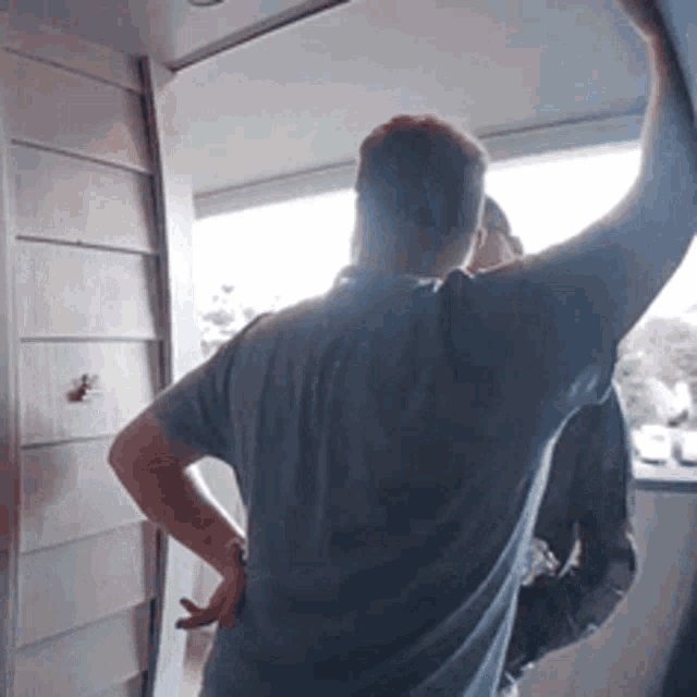 a man in a blue shirt stands in front of a door