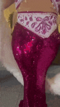 a woman is wearing a pink sequined dress with a white feather .