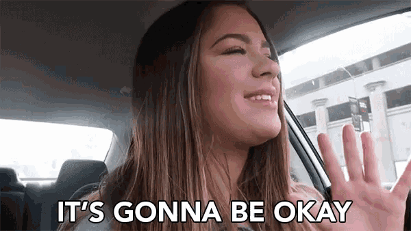 a woman is sitting in a car waving her hand and smiling .