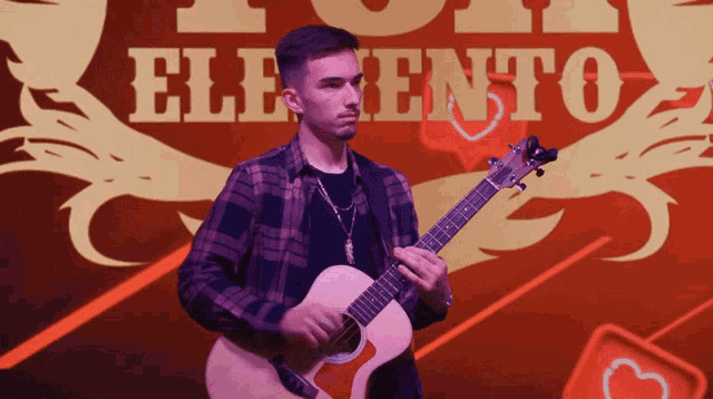 a young man playing a guitar in front of a sign that says " eliento "
