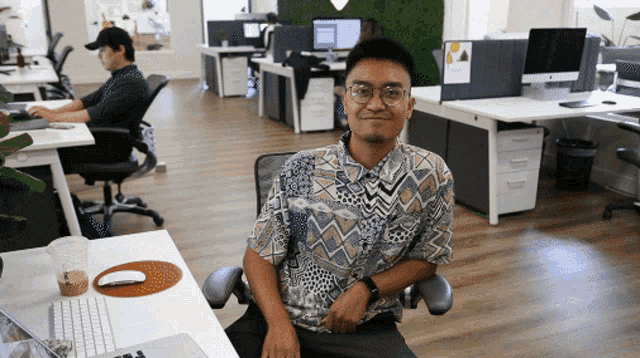 a man in a hawaiian shirt sits at a desk