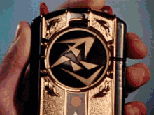 a person is holding a black and gold object with a ninja symbol on it