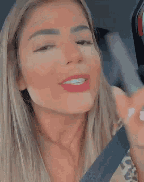 a woman in a car with her eyes closed is applying lipstick