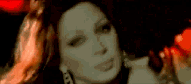 a close up of a woman 's face in a dark room with a red background .