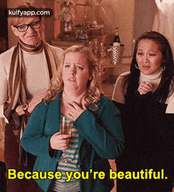 three women are standing next to each other and one of them is holding a glass of wine and saying because you 're beautiful .