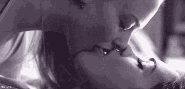 a couple of women are kissing in a black and white photo .