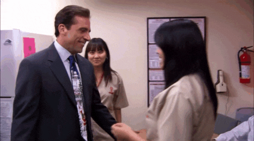 a man in a suit and tie is shaking hands with a woman in an orange uniform
