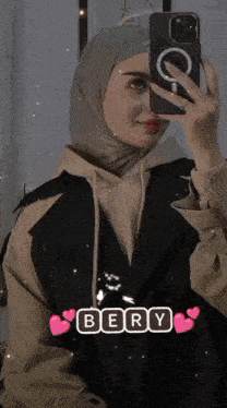 a woman in a hijab is taking a picture of herself with her phone