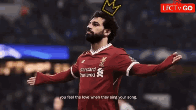 a soccer player with a crown on his head is wearing a standard chartered shirt