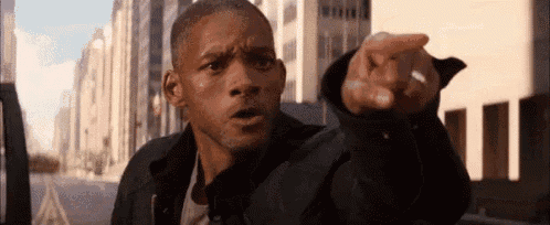 a man is pointing at the camera while wearing a ring on his finger .