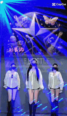 three women wearing masks are standing in front of a blue star .