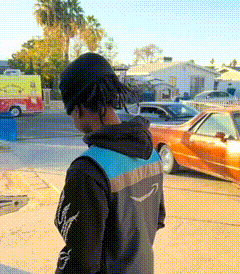 a person wearing an amazon jacket stands in front of a car