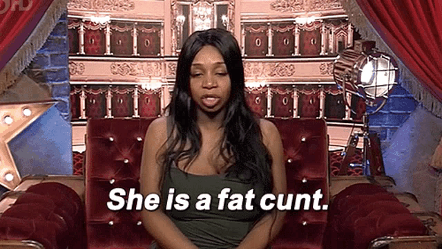 a woman is sitting in a chair with the words " she is a fat cunt " written below her