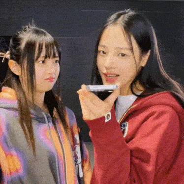 two girls are standing next to each other one is wearing a red hoodie with the letter s on it