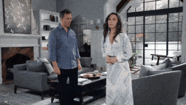 a man and a woman are standing in a living room looking at each other