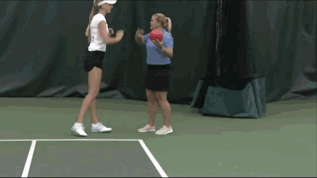 a woman holding a red ball talks to another woman