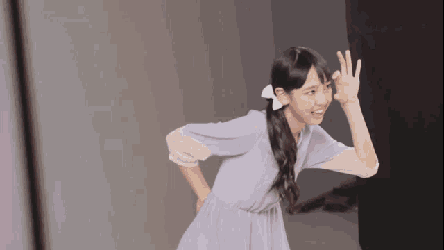 a girl in a purple dress with a bow on her hair is making a funny face