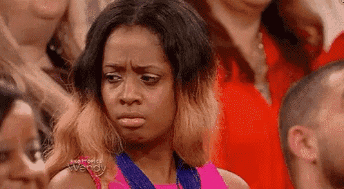 a woman is making a funny face while sitting in a crowd .