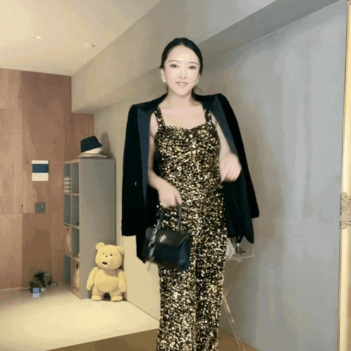 a woman in a sequined dress holds a black bag